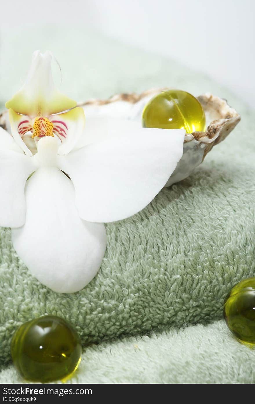 Olive oil bath pearls with orchid on green bath towels. Olive oil bath pearls with orchid on green bath towels.