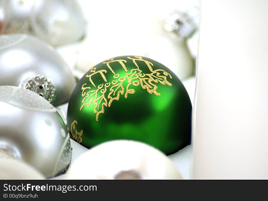 Shiny Green Christmas ornament still in the box, surounded by silver and white, waiting to be hung on the tree. Shiny Green Christmas ornament still in the box, surounded by silver and white, waiting to be hung on the tree.