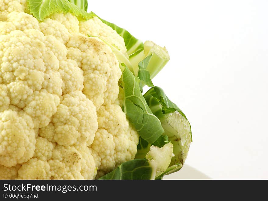 Close up of fresh raw cauliflower head surrounded by leaves.