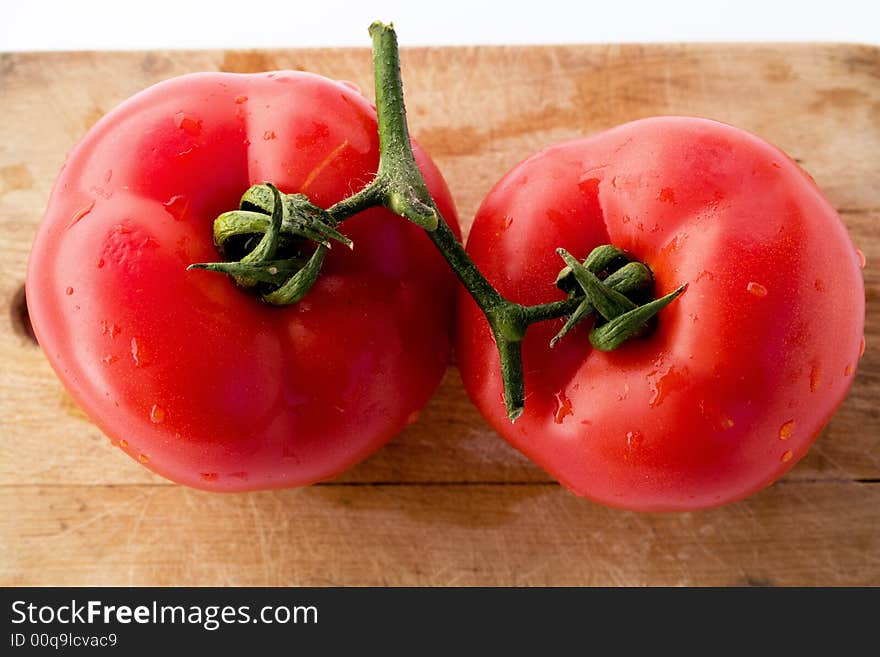 Tomatoes colorful, with water drops, on wooden board, studio shot. Tomatoes colorful, with water drops, on wooden board, studio shot