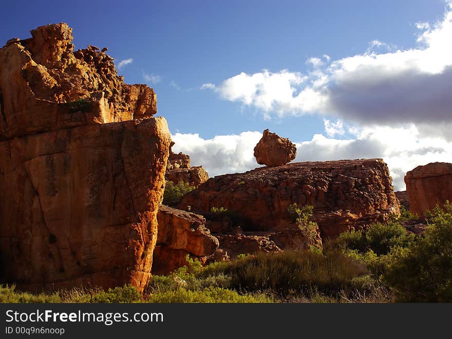 Yellow red stones and cliffs on red soil. Yellow sand and green bushes, deep blue cloudy sky. mountains of South Africa. Yellow red stones and cliffs on red soil. Yellow sand and green bushes, deep blue cloudy sky. mountains of South Africa