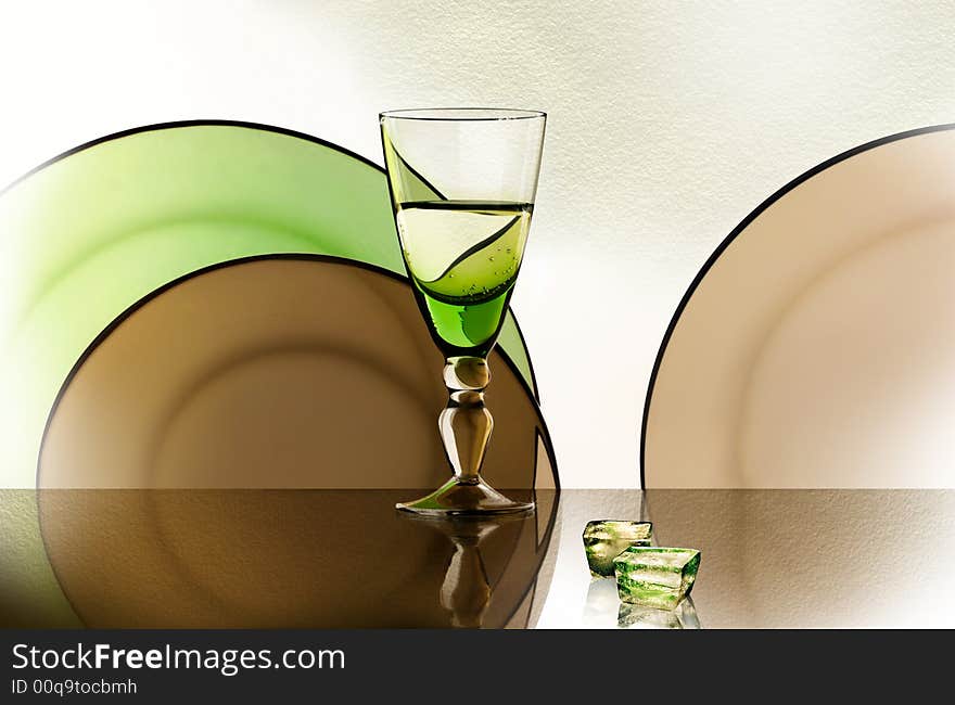 A glass beside a stack of white plates - on white background. A glass beside a stack of white plates - on white background