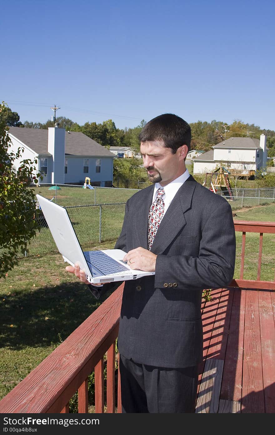 Young executive working at home through the internet ,standing on deck and communicating with his office computer. Young executive working at home through the internet ,standing on deck and communicating with his office computer