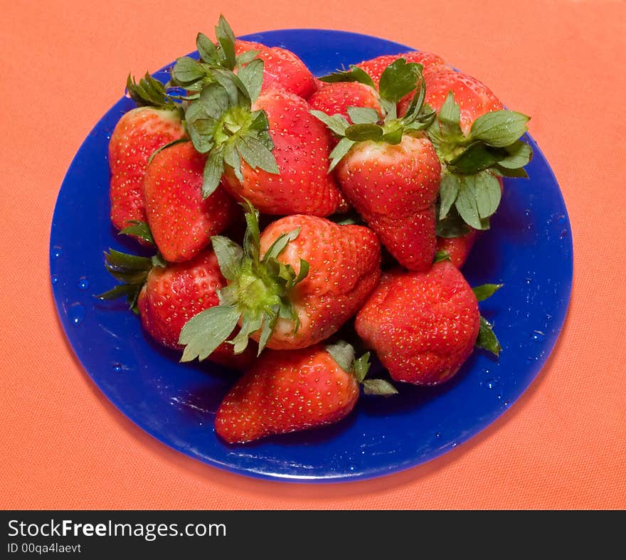 Still-life with fresh strawberry on the blue dish and orange background. Still-life with fresh strawberry on the blue dish and orange background