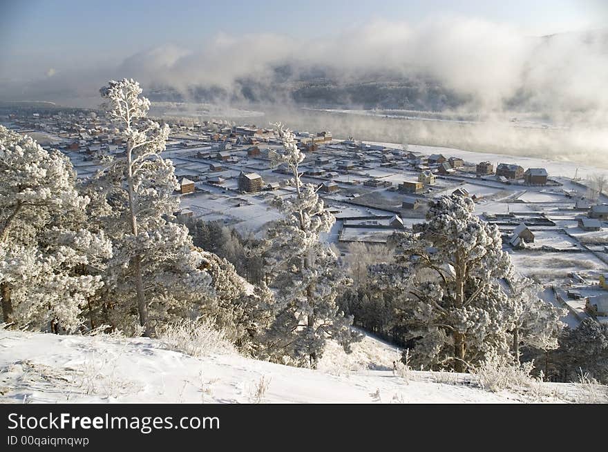 On a background of a winter landscape trees in snow. A fog.