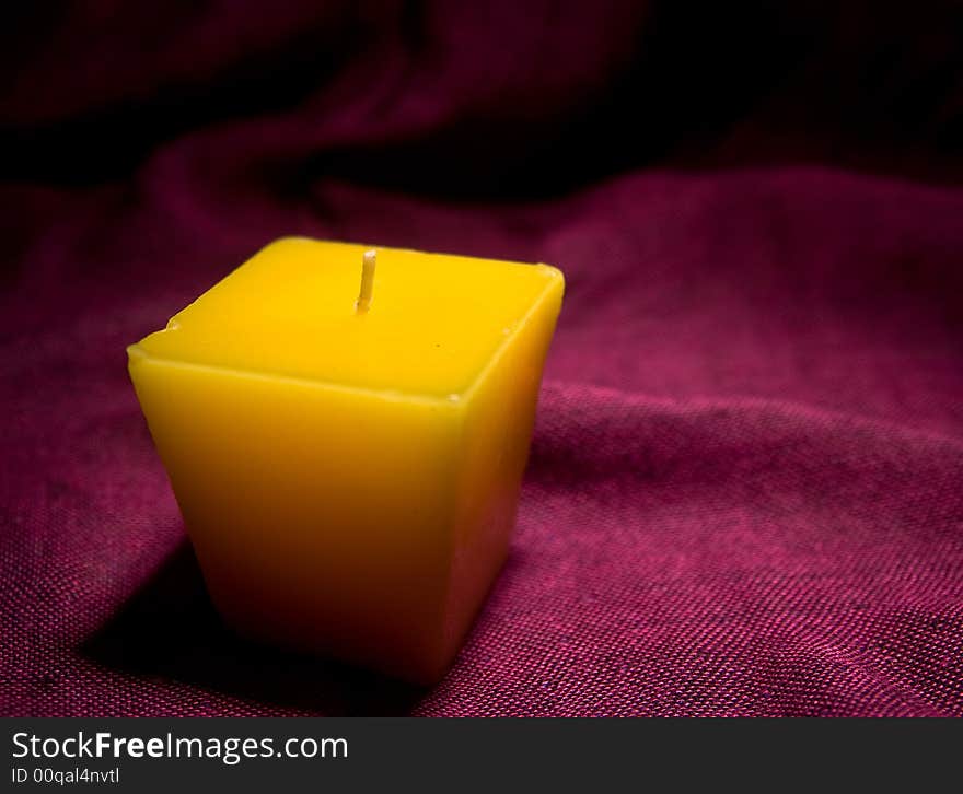 Single yellow candle without a light macro studio red background. Single yellow candle without a light macro studio red background