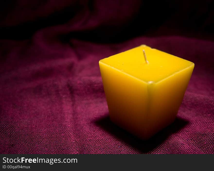 Single yellow candle without a light in red background macro. Single yellow candle without a light in red background macro