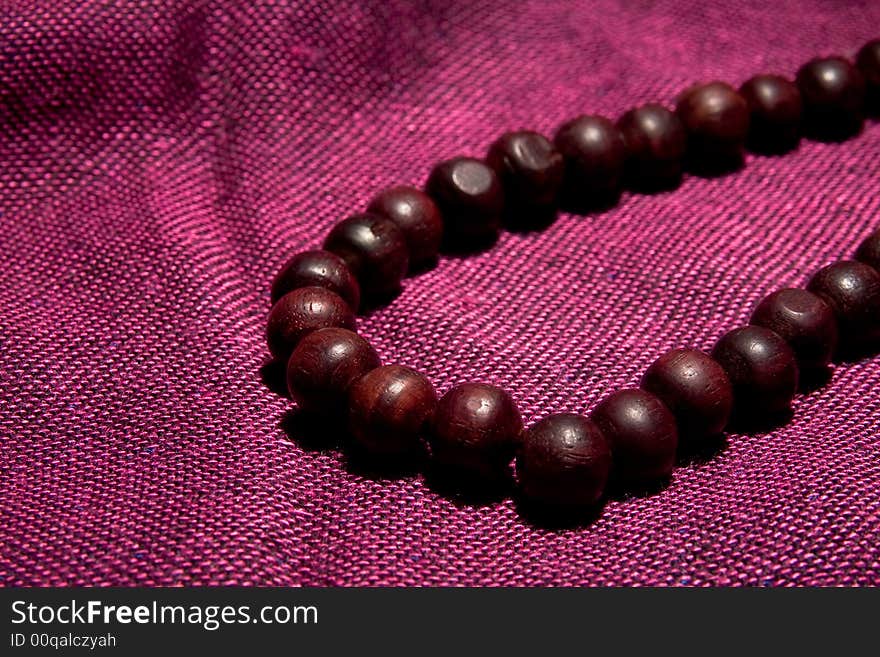 Wooden necklace on the red background macro close up