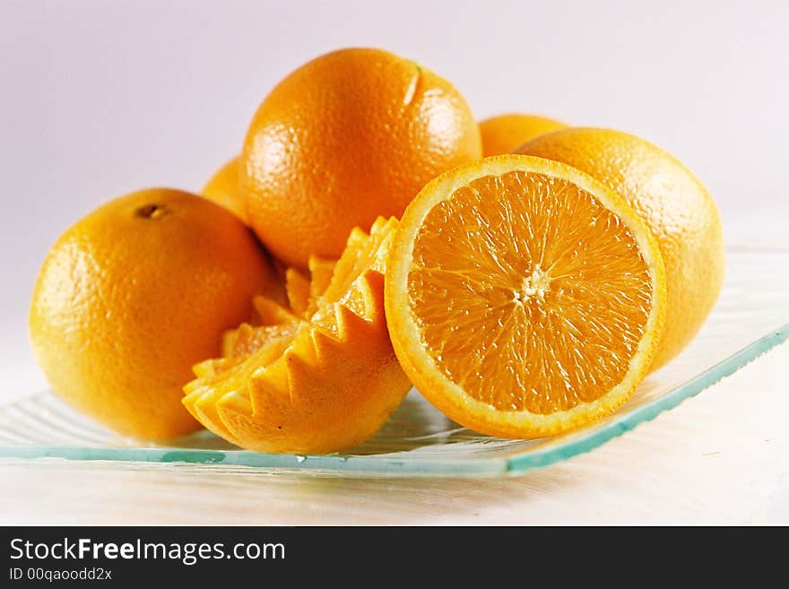 A plate of fresh oranges, whole and sliced