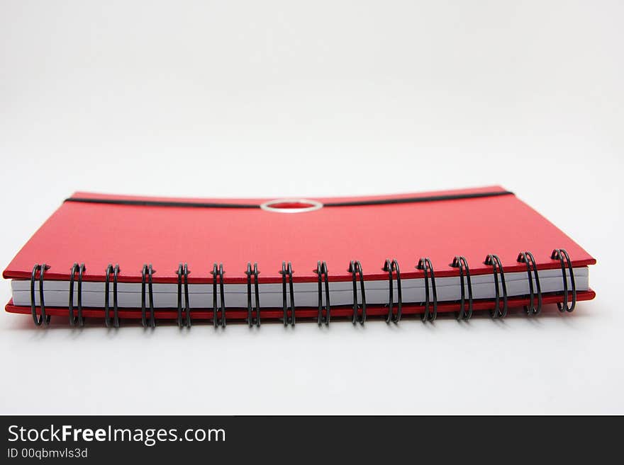 Red notebook lying closed on white