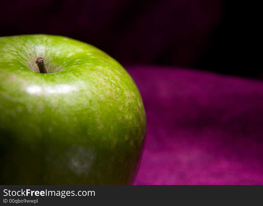 Single green apple on the red background macro close up. Single green apple on the red background macro close up