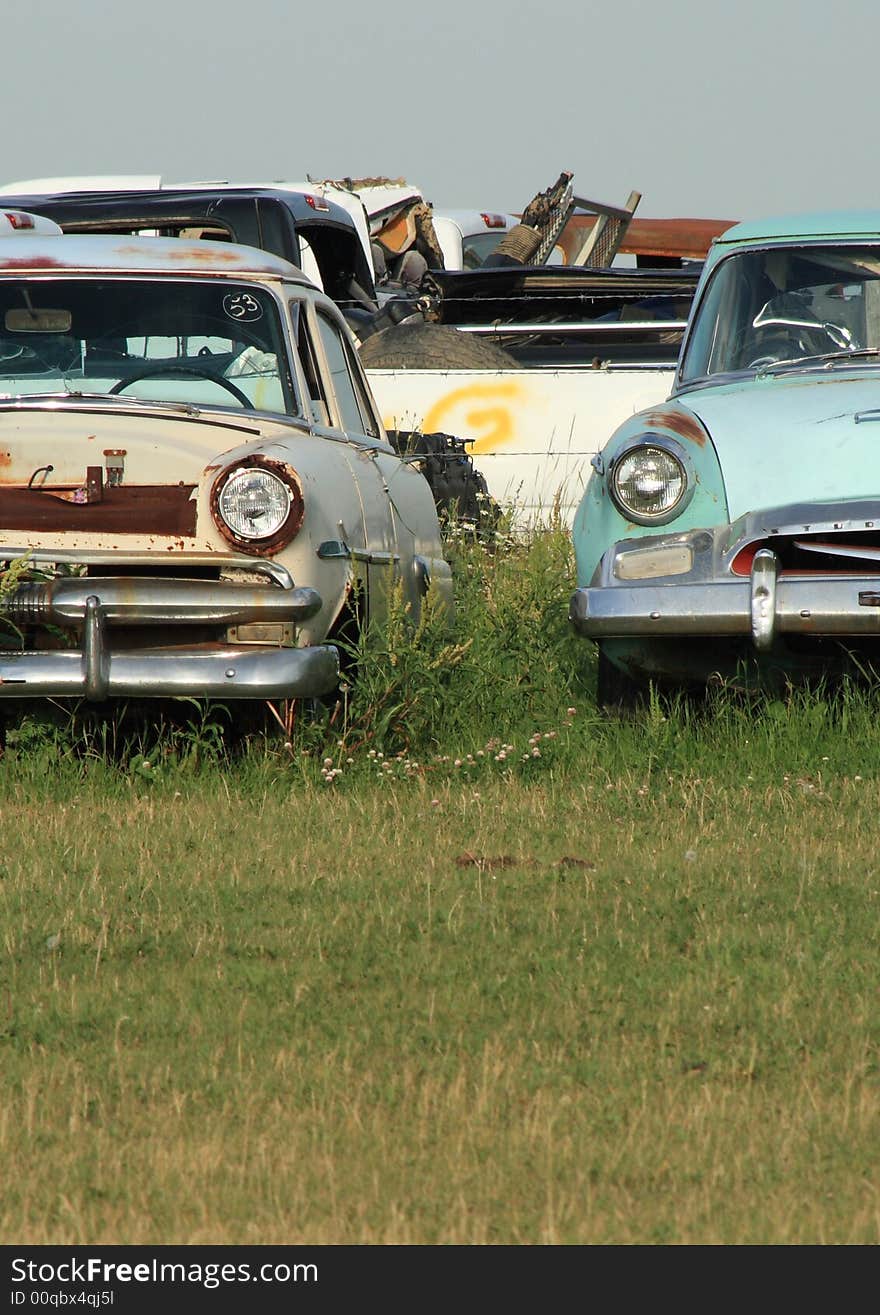 Detail of two old cars sitting in an auto wrecking yard. Detail of two old cars sitting in an auto wrecking yard