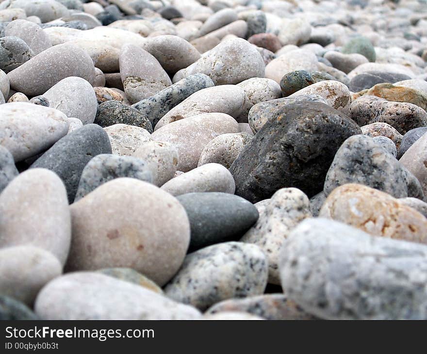 Gravel-stones on the beach shore. Most of pebble rocks has light-gray color with one black in the center. Gravel-stones on the beach shore. Most of pebble rocks has light-gray color with one black in the center.