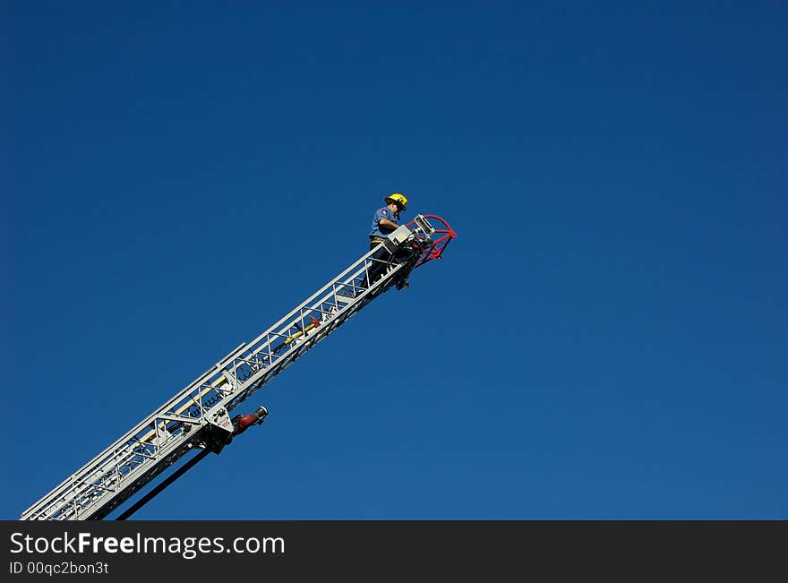 Firefighter at the top of a ladder truck's ladder. Firefighter at the top of a ladder truck's ladder