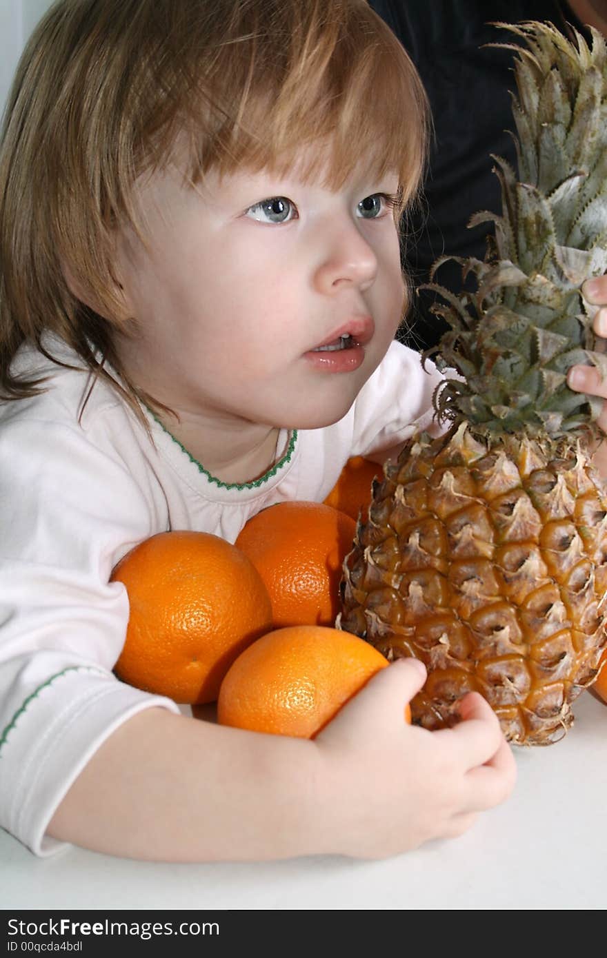 Girl holds in her hands oranges and pineapple. Girl holds in her hands oranges and pineapple