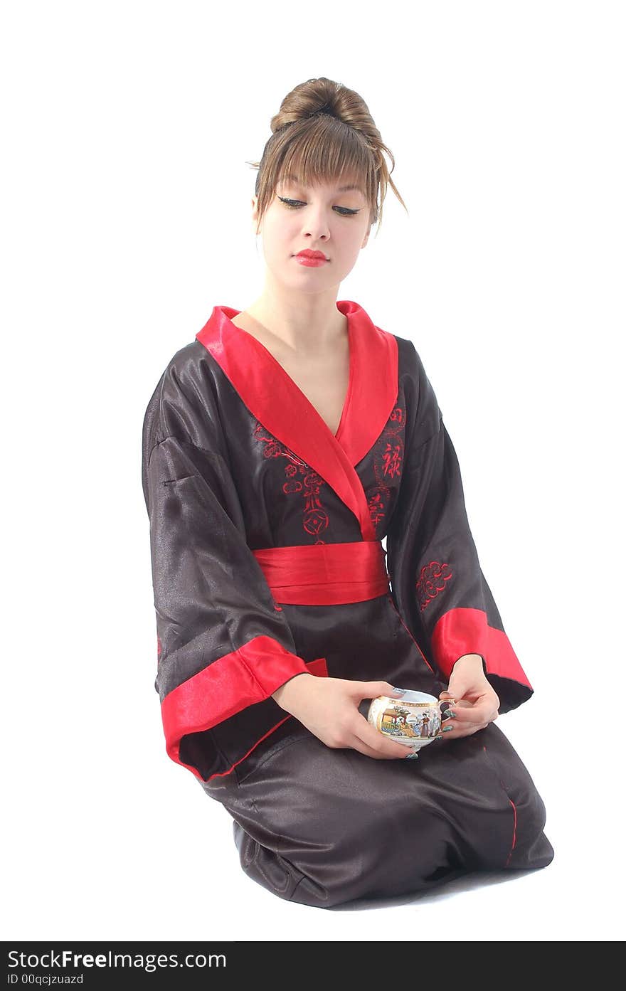 Attractive girl in kimono sitting with cup in hand. isolated over white. Attractive girl in kimono sitting with cup in hand. isolated over white