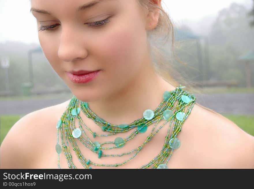 Beautiful Girl in fog wearing a green necklace. Beautiful Girl in fog wearing a green necklace