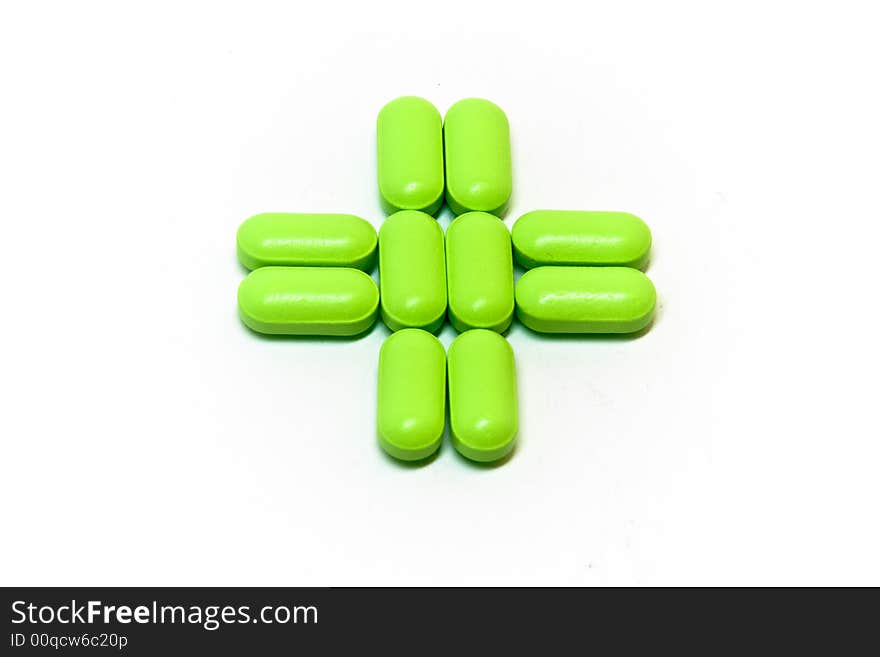 A green cross of pills on a white background