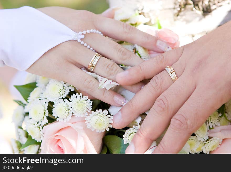 Two hands with wedding rings on the flower bouquet