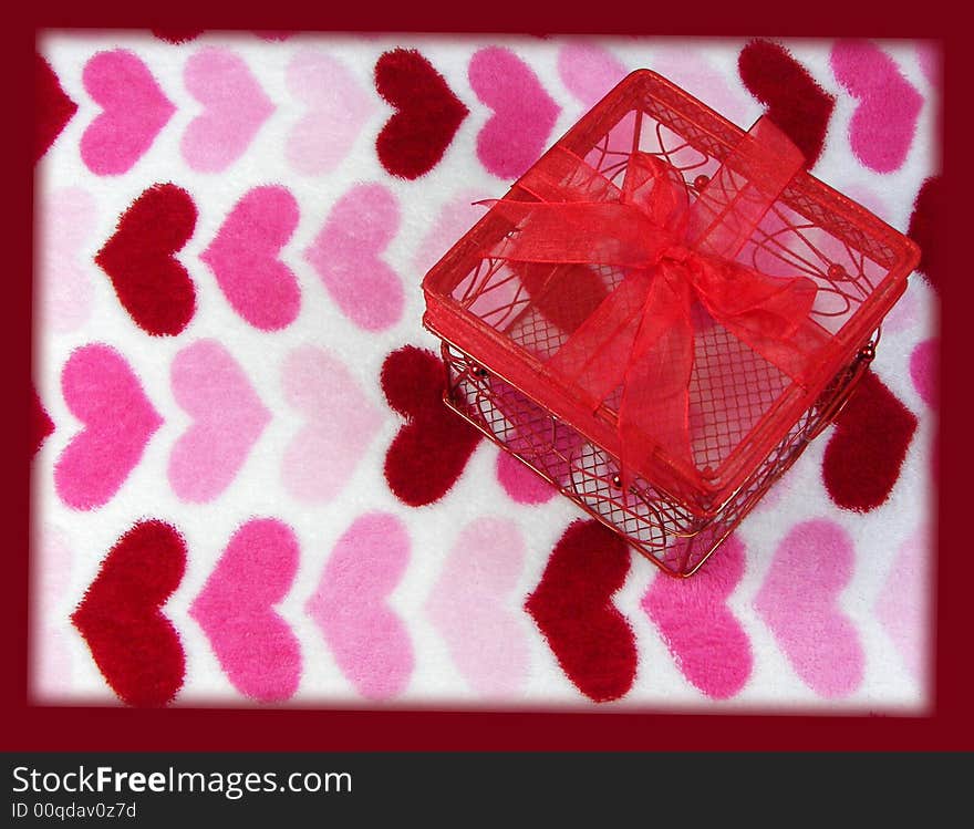 A red wire box with a bow on a fuzzy heart background with a dark red border. A red wire box with a bow on a fuzzy heart background with a dark red border.