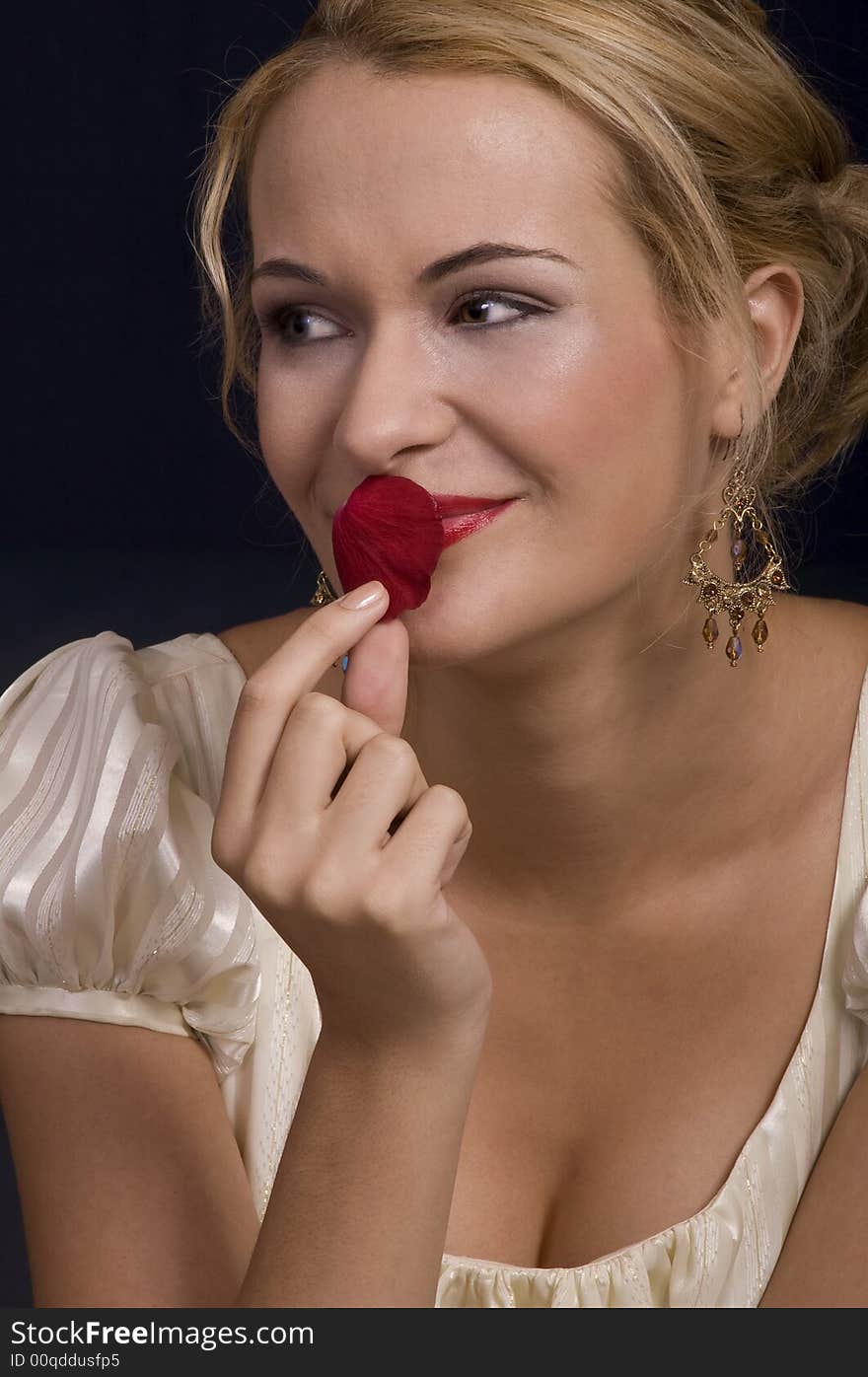 Beautiful blond girl kissing and smelling a rose petal wearing dress. Beautiful blond girl kissing and smelling a rose petal wearing dress