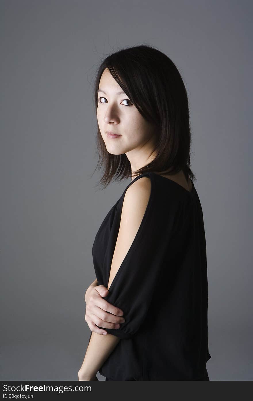 Young Asian woman wearing a black top standing three quarter to the viewer. Young Asian woman wearing a black top standing three quarter to the viewer.