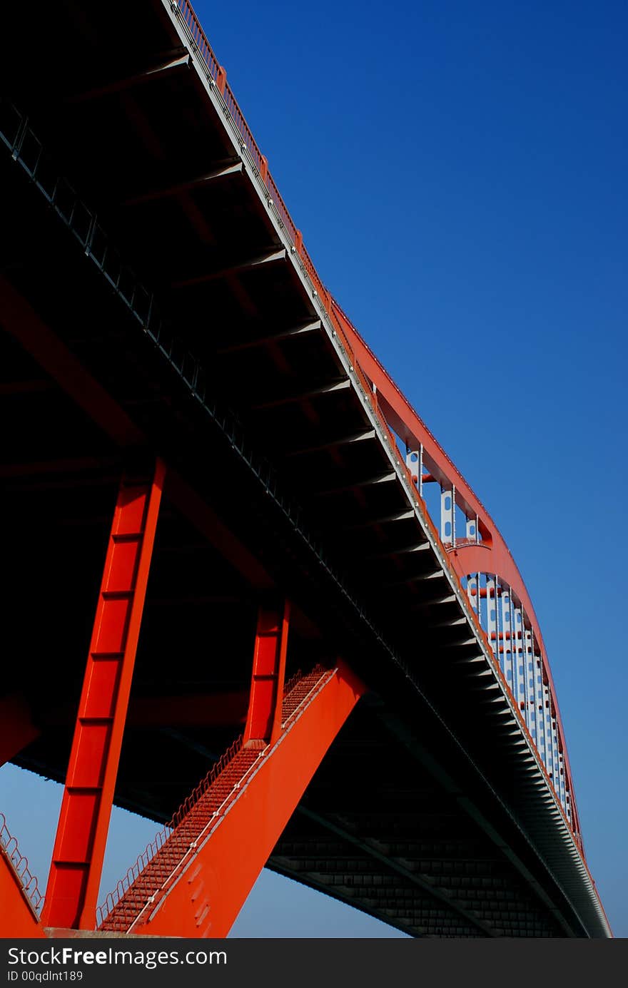 A steel bridge backgrounded with blue sky,striking contrast of colors,crimson,white,black,and blue