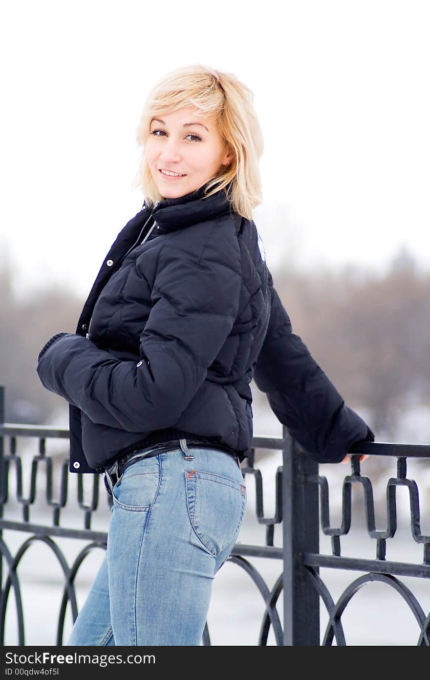 Young girl near open-work wall in winter park