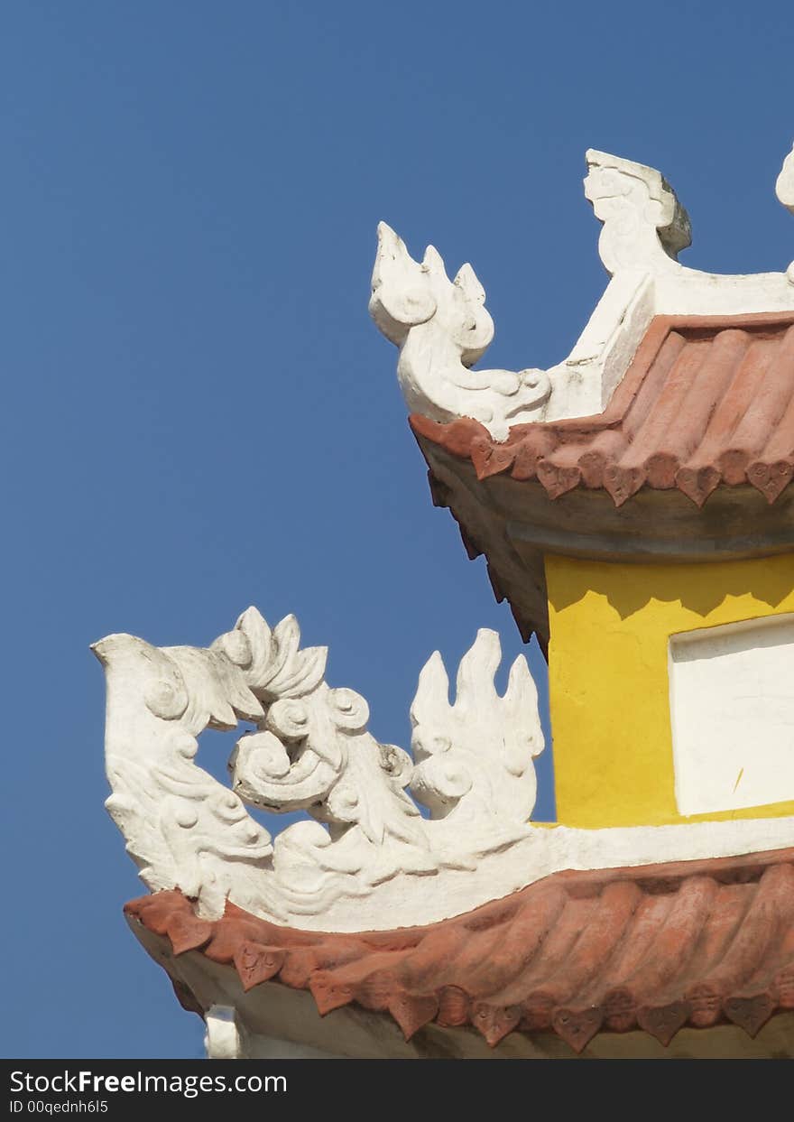 Detail of ancient, yellow Asian building on a blue sky background. Detail of ancient, yellow Asian building on a blue sky background.