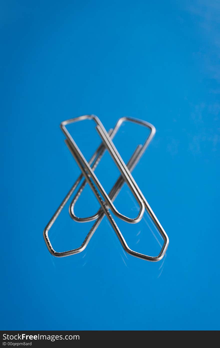 Paper clip over a blue reflective background