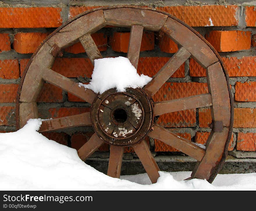 Wooden wheel costing in a snow about a wall
