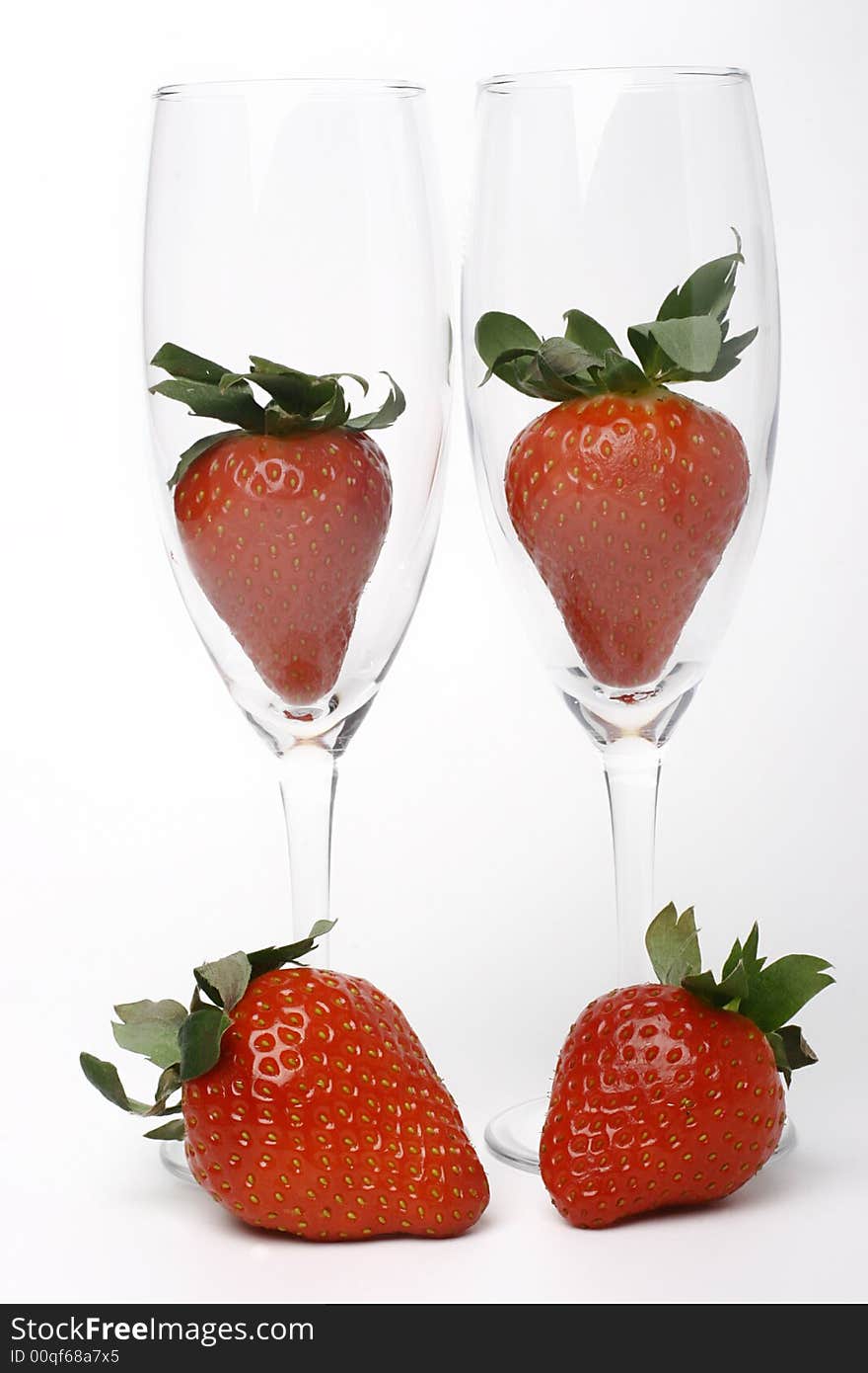 Four strawberries, two in glass, two beside glass. Four strawberries, two in glass, two beside glass