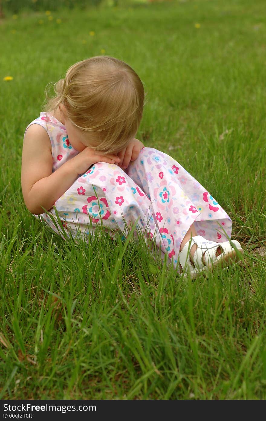 A preschool girl in a dress looking sad. A preschool girl in a dress looking sad.