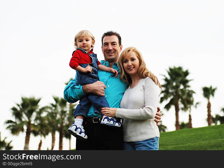 Happy couple with a child smiling in green park environment