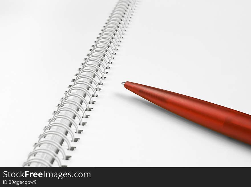 Open, blank spiral notebook with red plastic pen. Open, blank spiral notebook with red plastic pen.