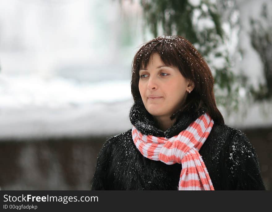 Portrait of the young woman under a falling snow