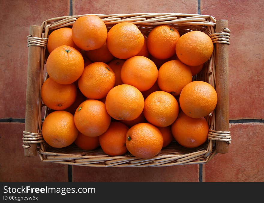 A basket of oranges on a terracotta tiled floor