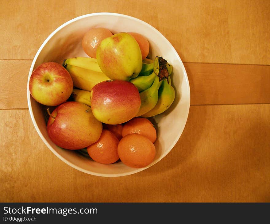 A bowl of fruit on a wooden table. A bowl of fruit on a wooden table