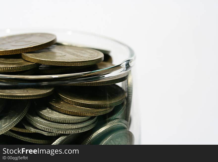 Close-up of multicolor coins in glass on the white background (isolated on white)