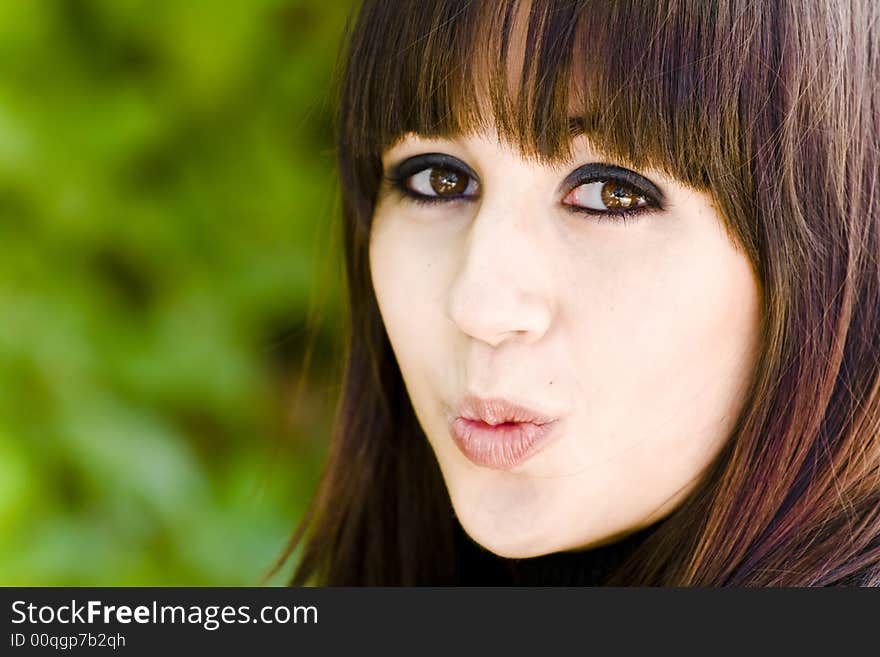 Kissing girl portrait against green background