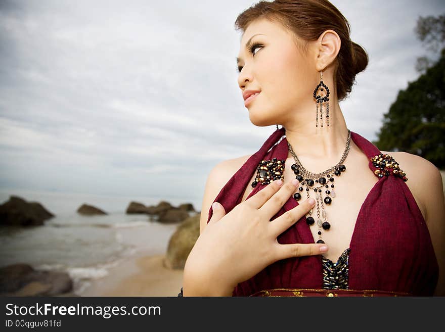 Young woman wearing accessories of ear rings and necklace by the sea side look out to the sea. Young woman wearing accessories of ear rings and necklace by the sea side look out to the sea