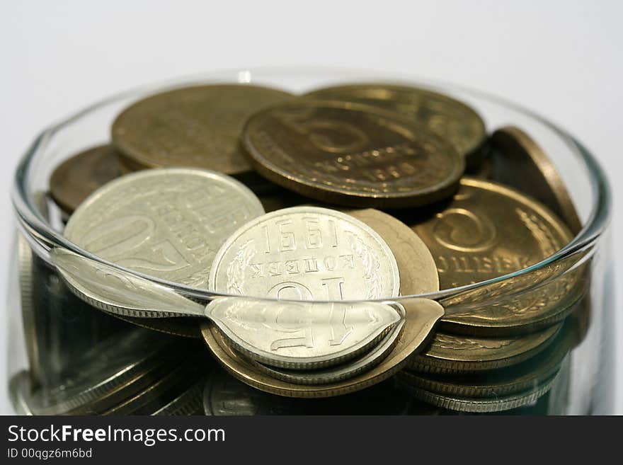 Close-up of multicolor coins in glass on the white background (isolated on white)