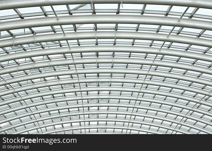 Curved reinforced steel roof joists in a conservatory with glass panes in between. Curved reinforced steel roof joists in a conservatory with glass panes in between.