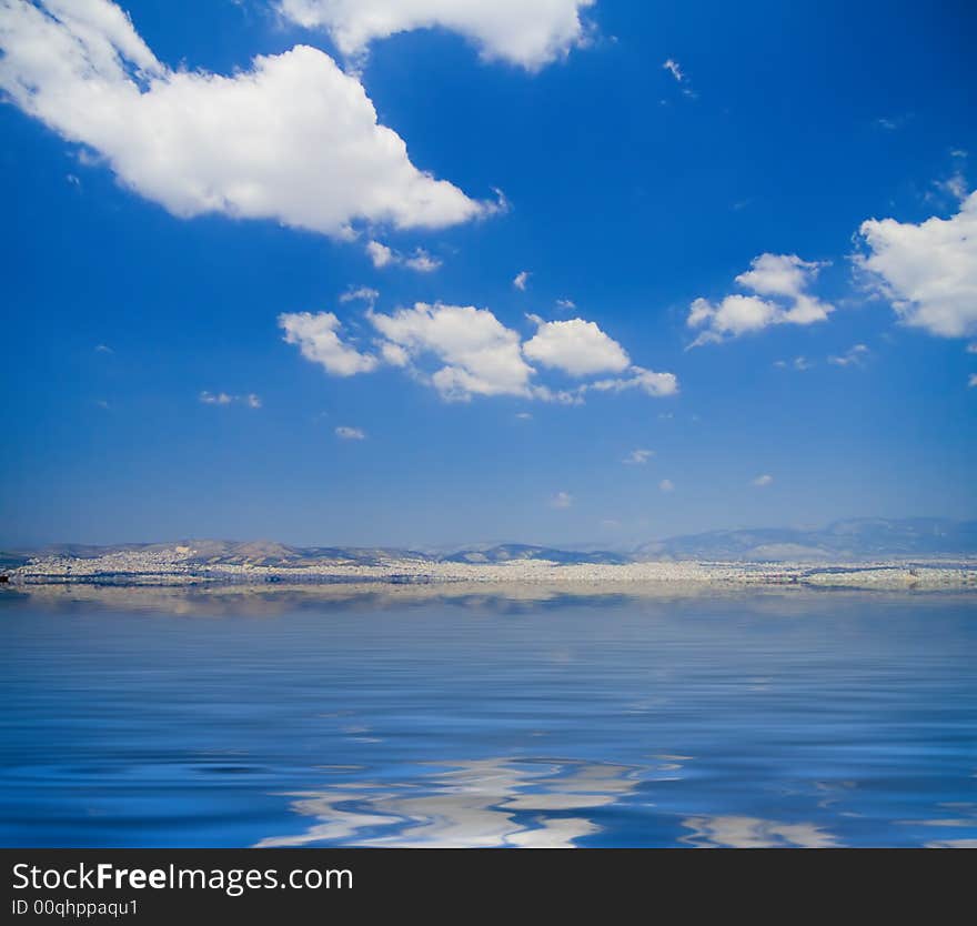 View of a shoreline from about five miles with fluffy clouds above. View of a shoreline from about five miles with fluffy clouds above