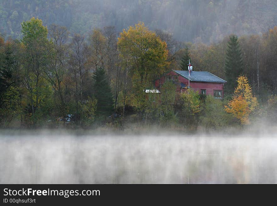 Small Red Wood house with myst over the water. Small Red Wood house with myst over the water