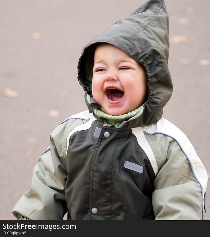 Happy shouting baby in green autumn jumpers with hood. Happy shouting baby in green autumn jumpers with hood