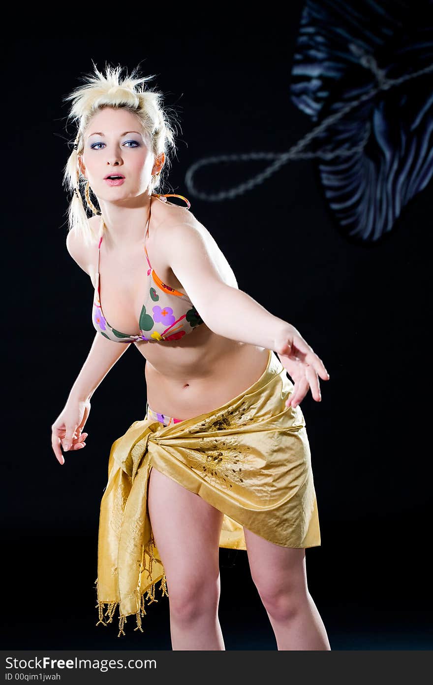 Woman throwing a cowboy hat with gold scarf wrapping her hips