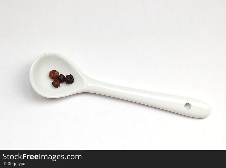 Some black pepper in spoon isolated