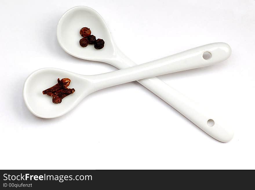 Black pepper&cloves in spoons isolated