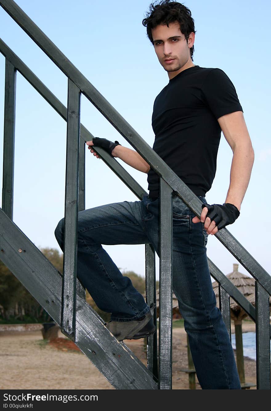 Young man climbing a wooden staircase at the beach